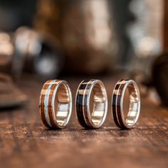 three wedding rings sitting on top of a wooden table