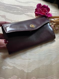 Dark maroon clutch/coin/wallet for the lady who loves fine leather goods.   Some of the finest leather goods to be found but more popular in Europe than here.   But once you have just one piece you'll recognize the difference between other popular brands here and this one. Darkest deep eggplant color similar to deep rich wine. Inside there is a full length kissing locks coin purse. In front of the coin section there is a 2 part compartment for cash or a sleeve for your credit cards.  A cash sleeve is often a bunch of clear sleeves to put photos or cards inside. Beyond the coin section there is another compartment with a slip pocket along the back wall of the wallet. There was a repair made at the right side, inside the gusset, to secure the leather to the lining behind it. 7 1/4" across 4" Maroon Clutch, Dark Maroon, Eggplant Color, Coin Purse Wallet, Leather Coin Purse, Clip Wallet, Popular Brands, Coin Wallet, Purse Accessories