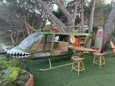 a green helicopter sitting on top of a lush green field next to a wooden table