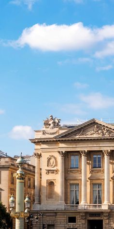 an old building with columns and statues in front of it on a clear blue sky day