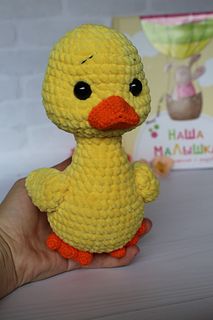 a small yellow crocheted duck sitting on top of a table