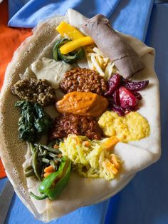 a tortilla filled with lots of different types of food on top of a blue table cloth