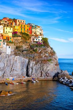 the colorful houses are perched on top of the cliff above the water's edge