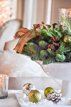 a christmas centerpiece with evergreen, pine cones and baubles on a table