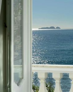 an open window looking out at the ocean and land in the distance from a balcony