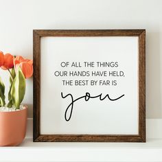 a wooden frame sitting on top of a shelf next to a potted plant and an orange flower