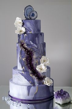 a three tiered purple cake with white flowers