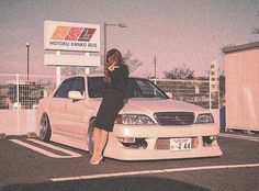 a woman leaning on the hood of a white car