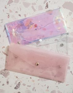 two clear cases sitting next to each other on top of a marble countertop with confetti sprinkles