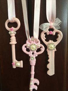 three key ornaments hanging on a door with ribbons and bows attached to the doors handles