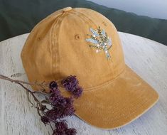 a brown hat sitting on top of a wooden table next to dried flowers and a green pillow