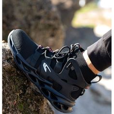 a person's foot wearing black sneakers on top of a rock