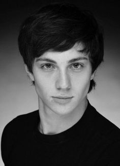 a black and white photo of a young man with short hair wearing a black shirt