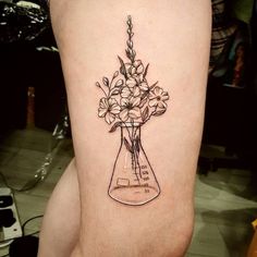 a tattoo with flowers in a vase on the thigh