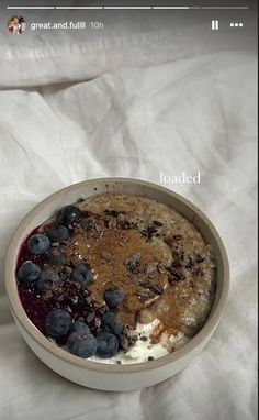 a bowl filled with oatmeal and blueberries on top of a white sheet