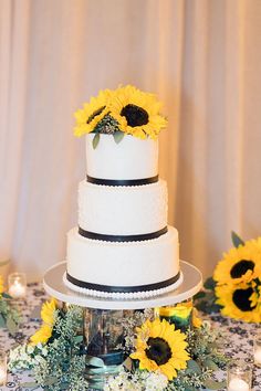 a white wedding cake with sunflowers on top