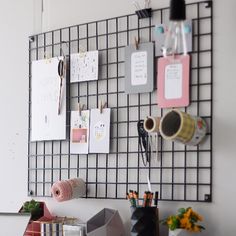 a desk with several office supplies on it, including pens and pencils in front of a grid wall