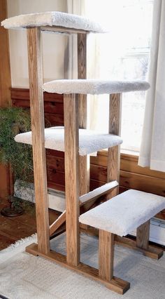 the cat tree is made out of wood and has white fur on it's top