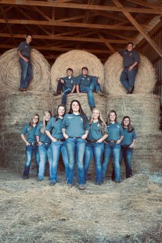 a group of people standing on top of hay bales in front of a barn