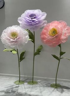 three pink and two purple flowers in vases