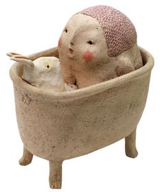 a ceramic figurine sitting in a bathtub with an infant doll inside it