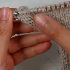 someone is crocheting the ends of a piece of yarn with their fingers and thumbnails