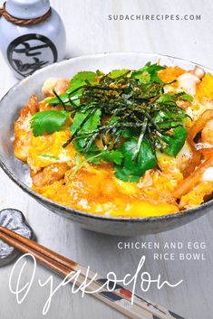 a bowl filled with rice and vegetables on top of a table next to chopsticks