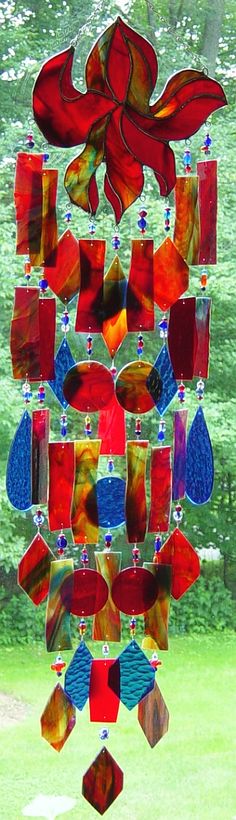 a colorful wind chime hanging from the side of a tree in front of a green field