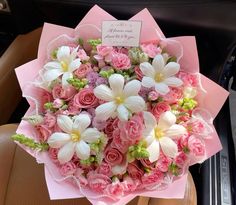 a bouquet of pink and white flowers in the back seat of a car with a note on it