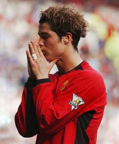 a soccer player is holding his hands together and praying in front of an audience at a stadium