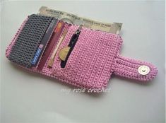 a pink wallet with two credit cards and a pen in it on a white surface