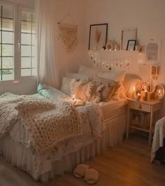 a bedroom with white furniture and lights on the windows sill above the bed is lit up by candles