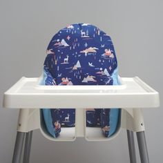 a high chair with a blue and white seat cover on it's back, in front of a gray wall