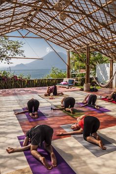 a group of people doing yoga on mats under a roof with mountains in the background