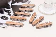 six personalized wooden bottle openers sitting next to a cup and saucer on a table