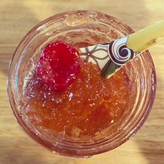 a glass filled with liquid and a straw sticking out of it's top, sitting on a wooden table