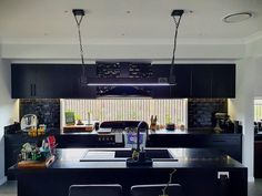 a kitchen with black cabinets and an island in the middle is lit by two pendant lights