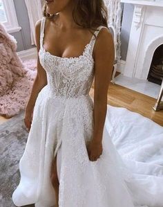 a woman in a white wedding dress standing next to a fireplace with her leg up on the floor