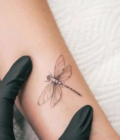 a woman's arm with a tattoo that has a dragonfly on the side