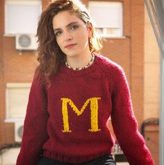 a woman wearing a sweater with the letter m on it