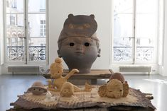 several clay animals are on display in front of a large head and window sill