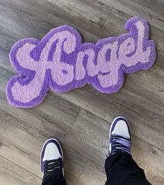 someone standing on the floor with their feet up in front of an area rug that says angel