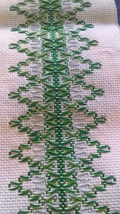 a cross stitched christmas tree is shown on a piece of white fabric with green trim