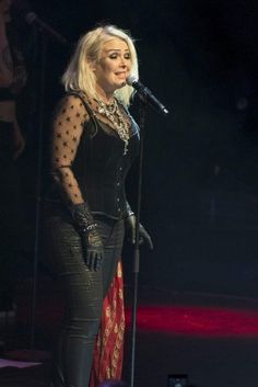 a woman in black outfit on stage with microphone