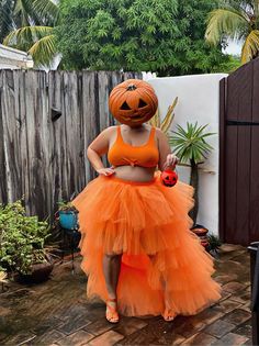 a woman in an orange dress wearing a pumpkin costume