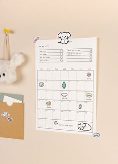 a white teddy bear sitting on top of a desk next to a calendar and other items