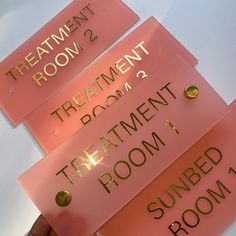 there are three pink signs that say treatment room, treatment room and sunbed room