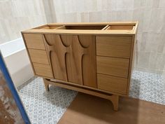 a wooden cabinet sitting on top of a tiled floor