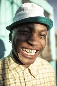 a smiling man wearing a green and white hat with his eyes wide open to the camera