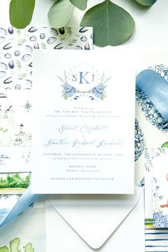 the wedding stationery is laid out on top of some cards and papers with leaves